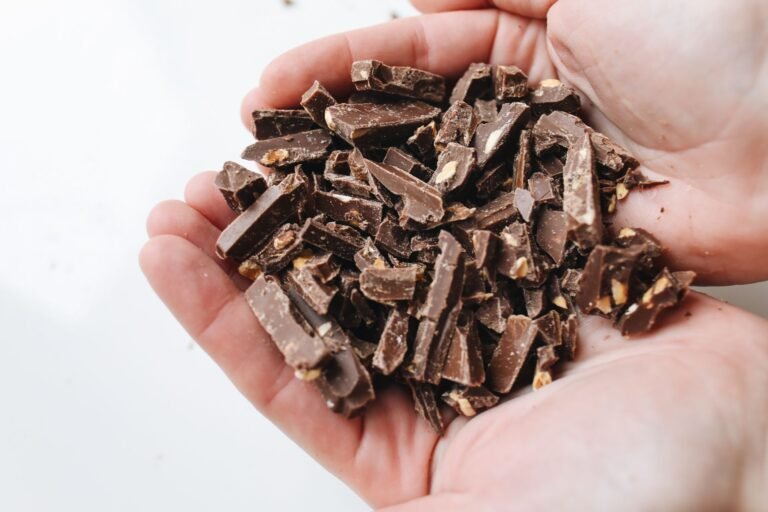 Chopped dark chocolate pieces held in hands close-up